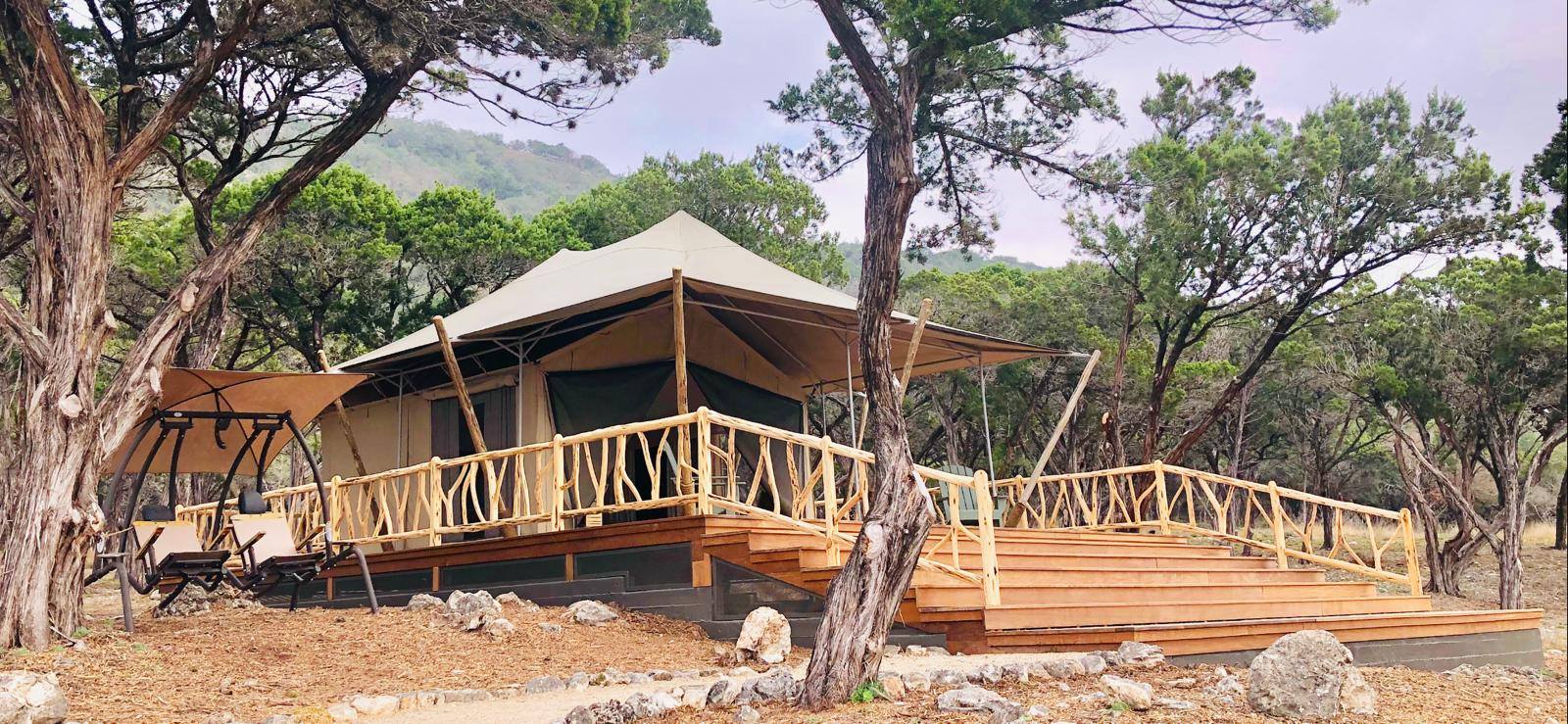 Glamping tent on wooden deck in mountains with a covered swing